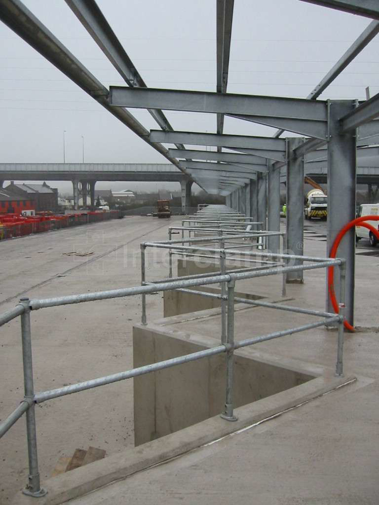 Interclamp pipe clamp fittings and tubes assembled into a robust safety guardrail at a civic recycling center, offering secure pathways for visitors.